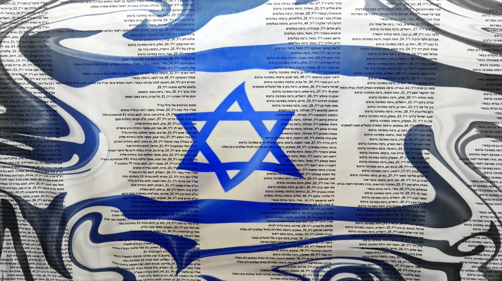Bandera de Israel con los nombres de víctimas, en una exhibición conmemorativa del festival Nova. Foto: Wikimedia Commons.